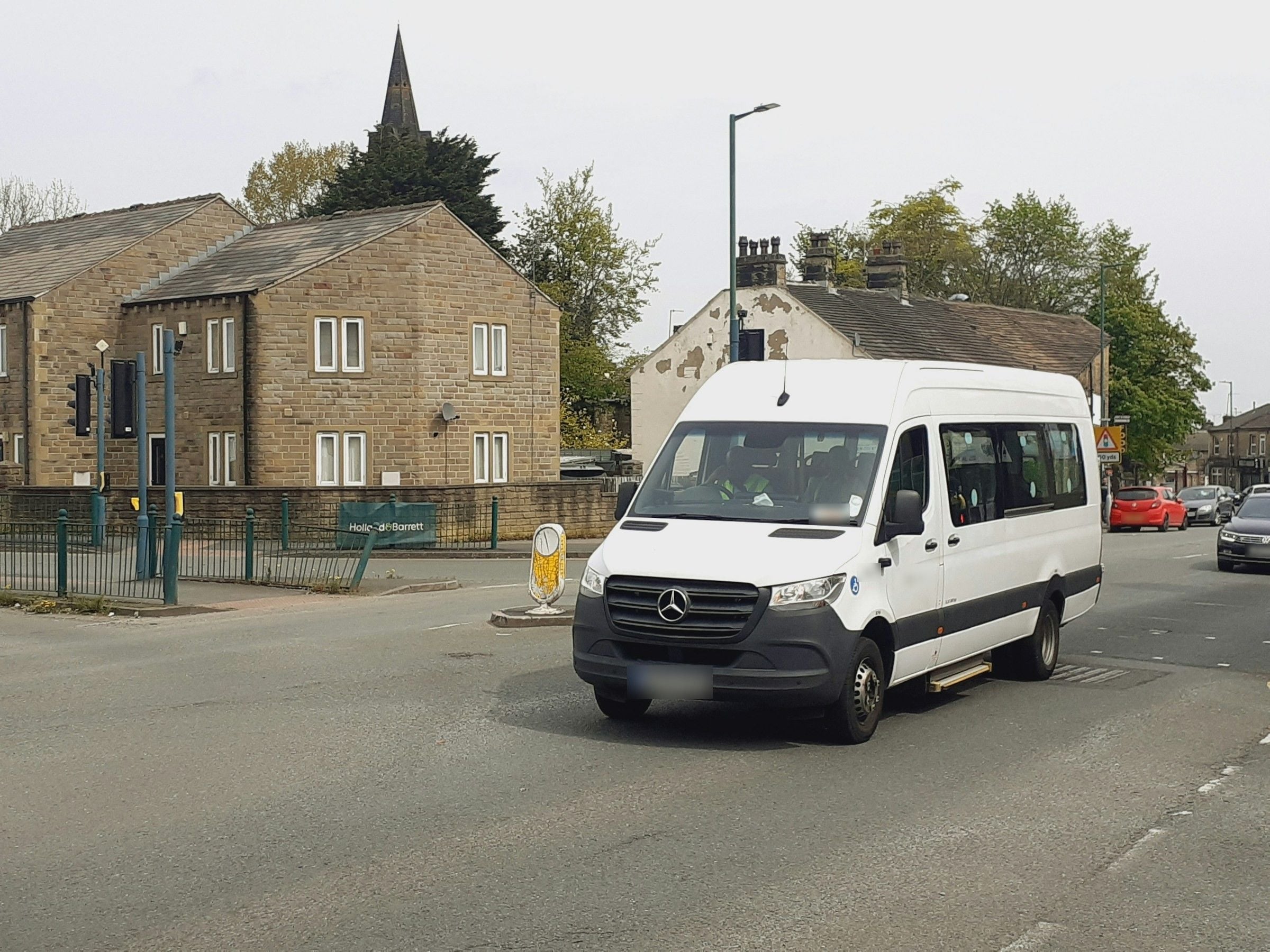 White minibus driving through a town street